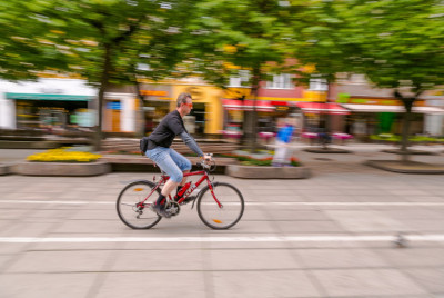 Cyklista na bicykli jazdí po vyhradenej ceste pre cyklistov cez mesto so stromami v pozadí